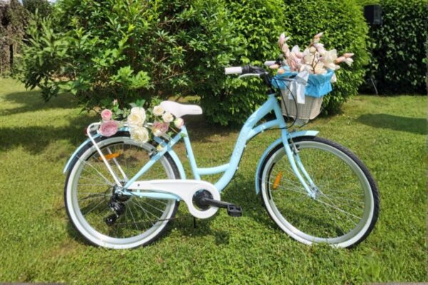 Sininen polkupyörä kukkakoristeilla puutarhassa